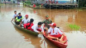 Akibat Banjir, Babinsa Bantu Anak – anak Kesekolah Gunakan Perahu