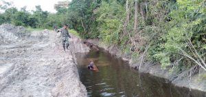 Anggota TNI dan Warga Bawa Kayu Untuk Jembatan Melalui Sungai